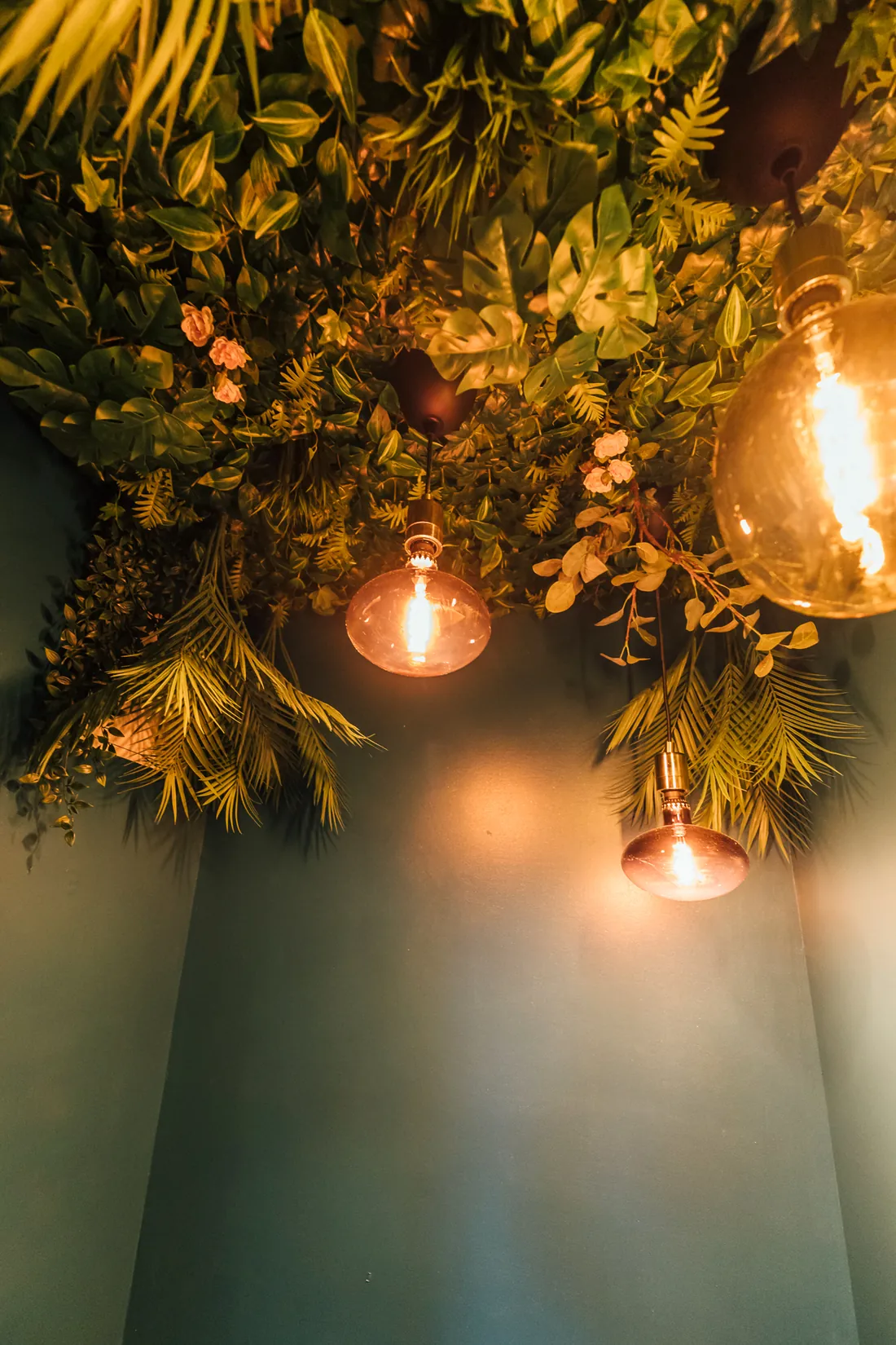 Stimmungsvolle Pflanzendecke mit goldenen Pendelleuchten im Salon